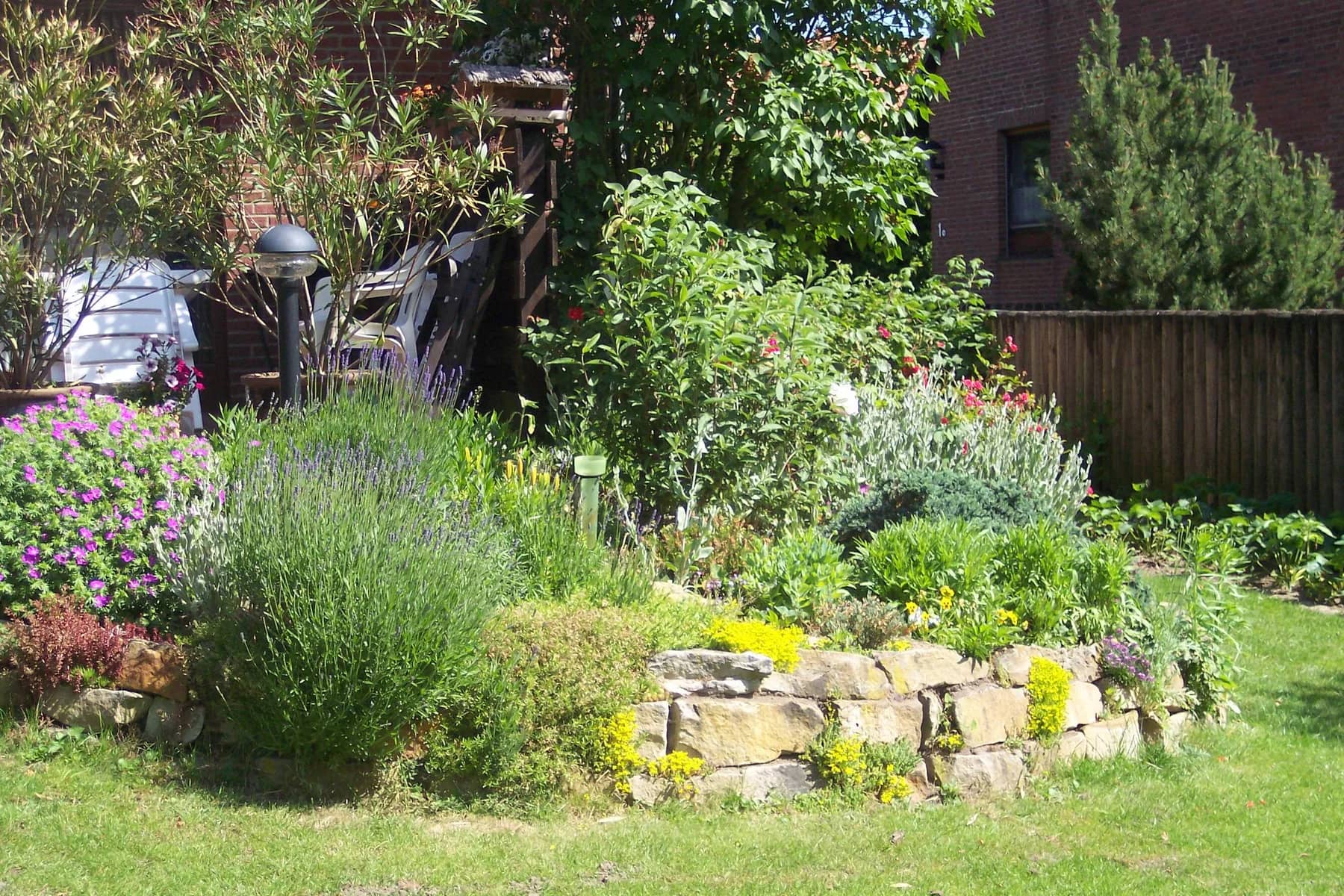 Blühende Stauden und eine Natursteineinfassung in einem angelegten Garten