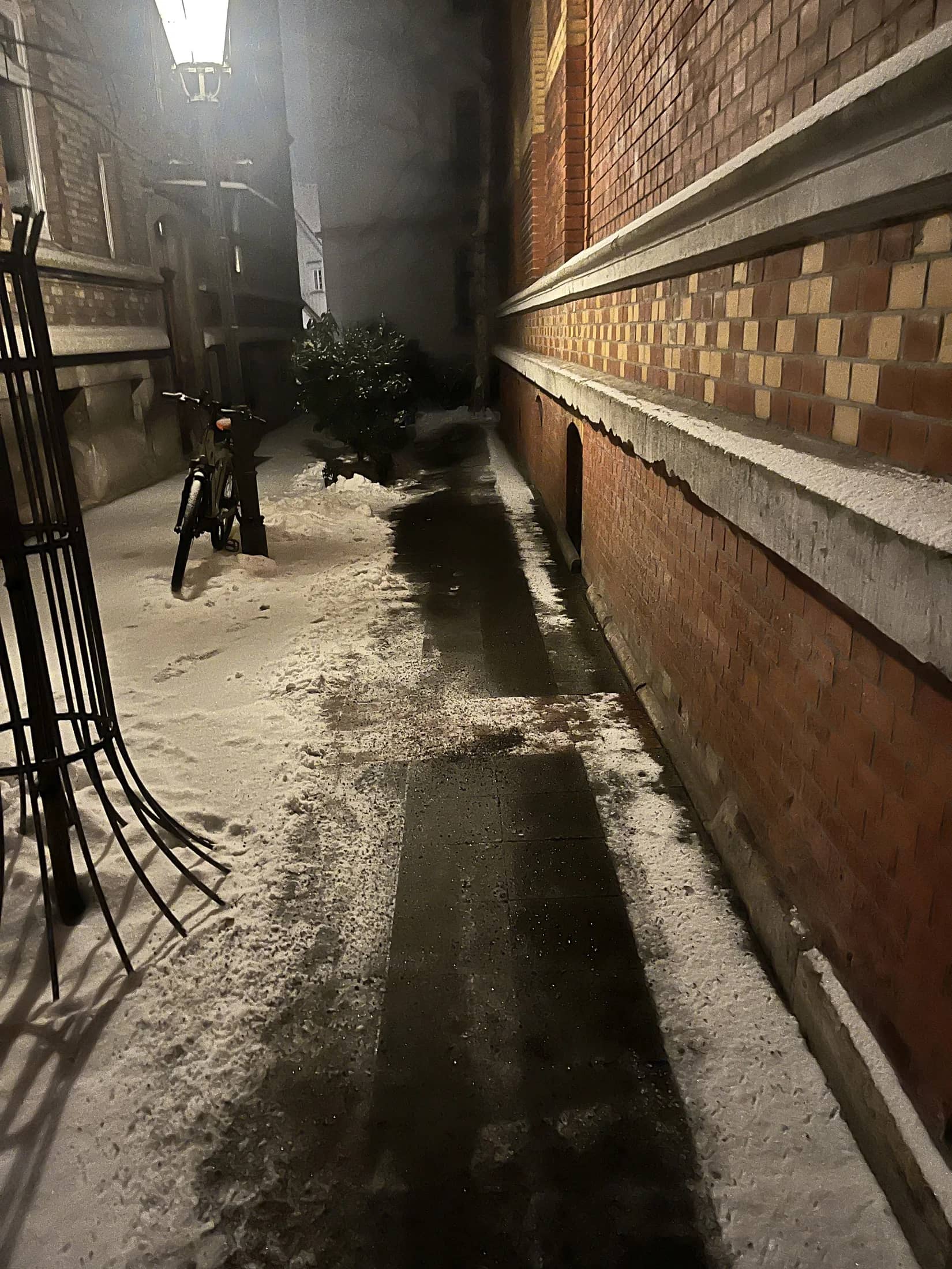 Geräumter Durchgang neben einer Backsteinmauer bei Nacht
