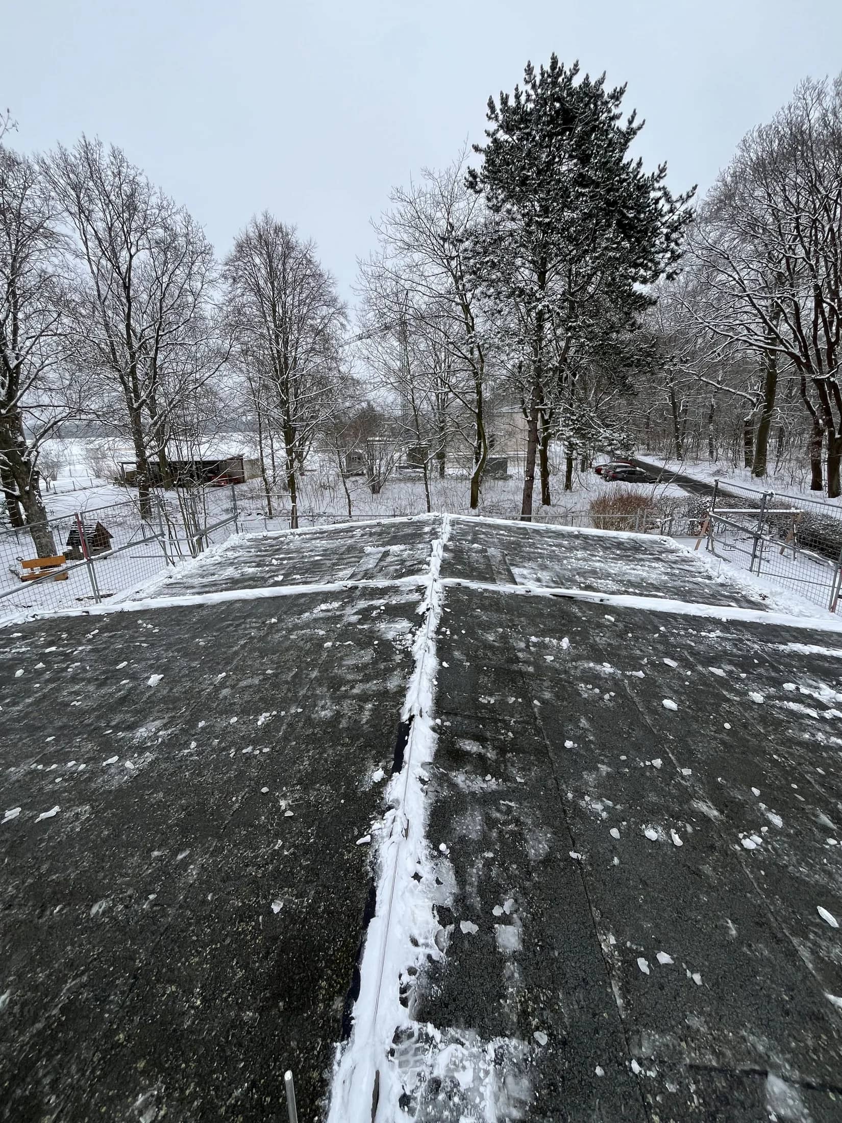 Geräumter Weg zwischen schneebedeckten Grünflächen und Bäumen
