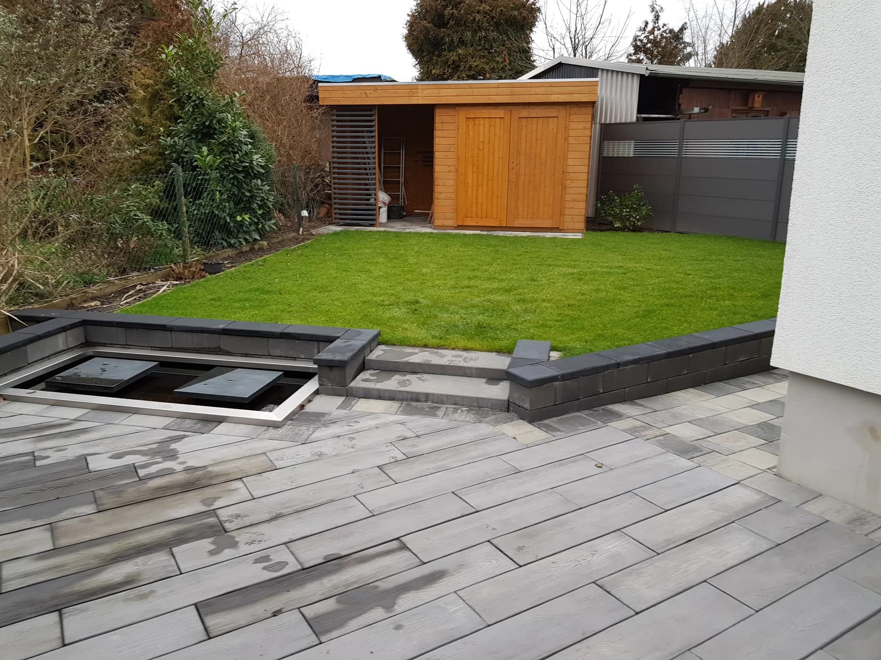 Neu gepflasterte Terrasse mit Rasen und Gartenhaus