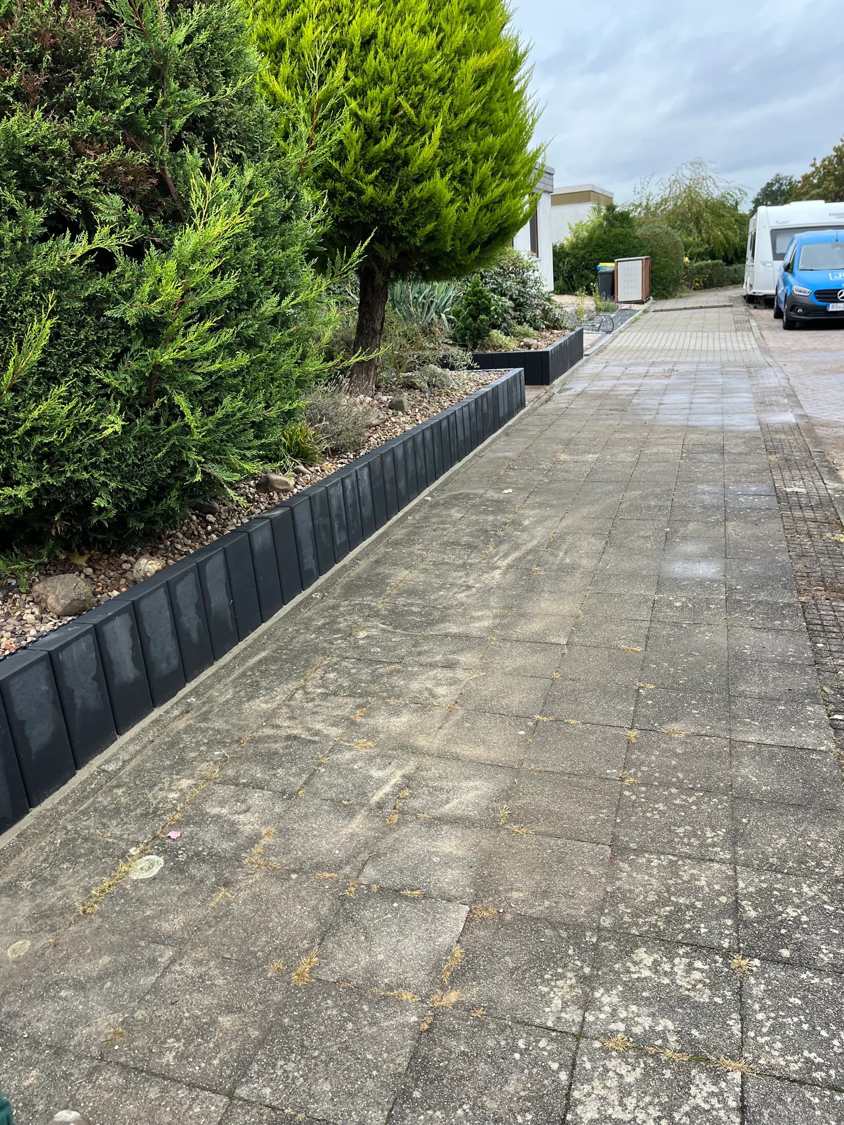 Niedrige Gartenmauer entlang einer gepflasterten Einfahrt