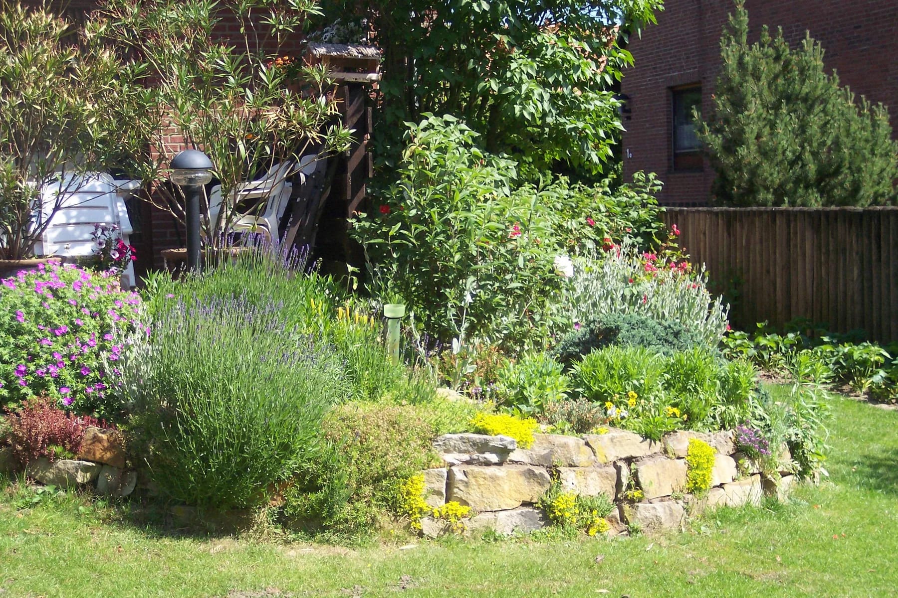 Blühende Stauden und eine Natursteineinfassung in einem angelegten Garten