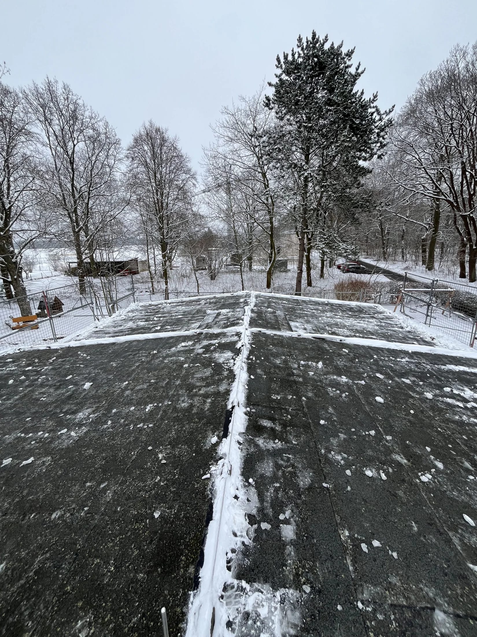 Geräumter Weg zwischen schneebedeckten Grünflächen und Bäumen